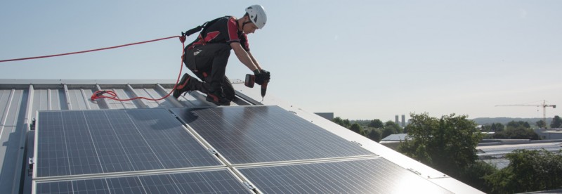 Gegen Absturz gesicherter Solar-Installateur auf einem Steildach